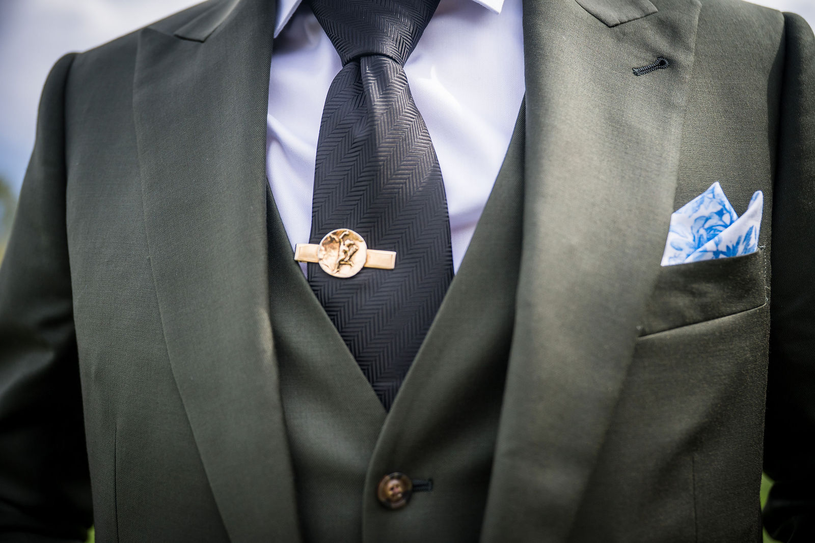 Boutonniere and pocket square detail on an olive green wedding suit