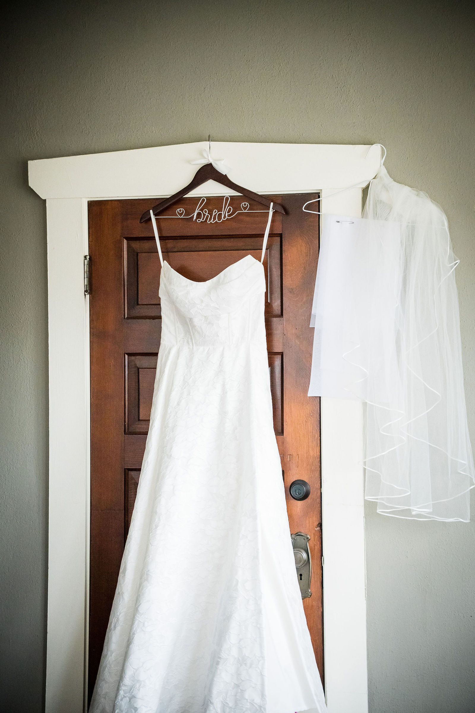 Wedding dress hanging on a door in the getting ready house at the Manor House