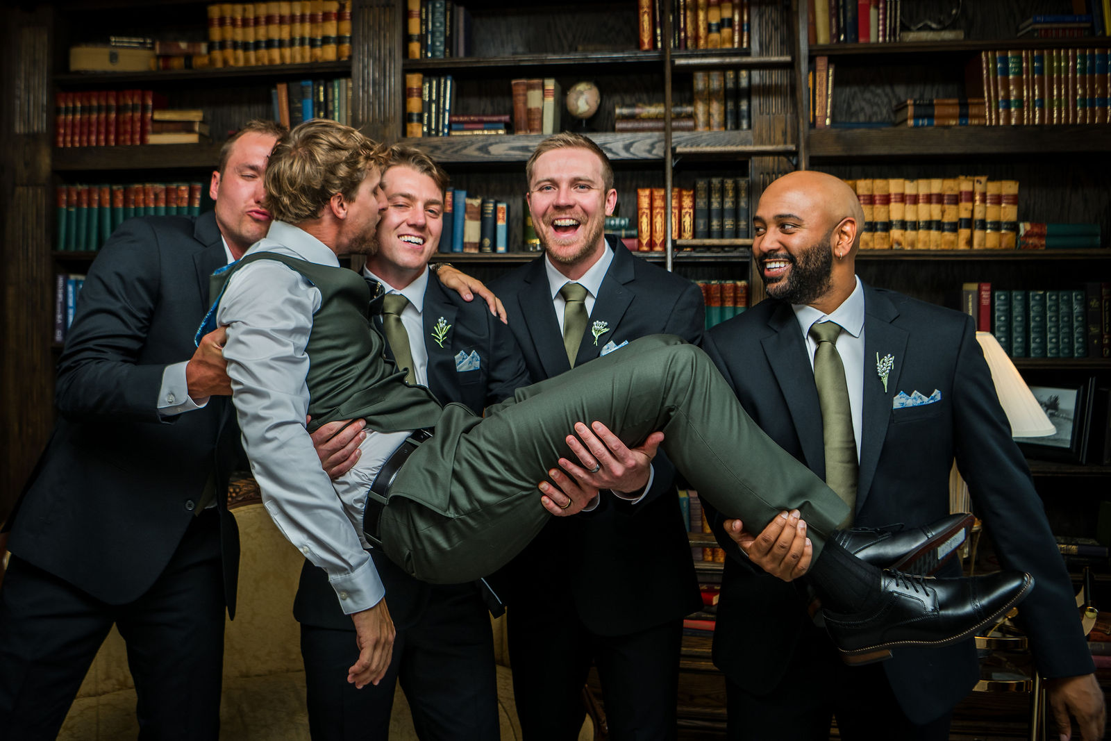 Groomsmen lifting the groom in the Manor House library