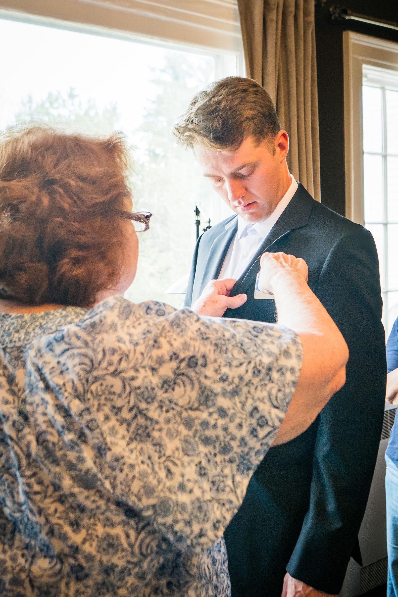 Mother of the groom pinning her son’s boutonniere before the ceremony