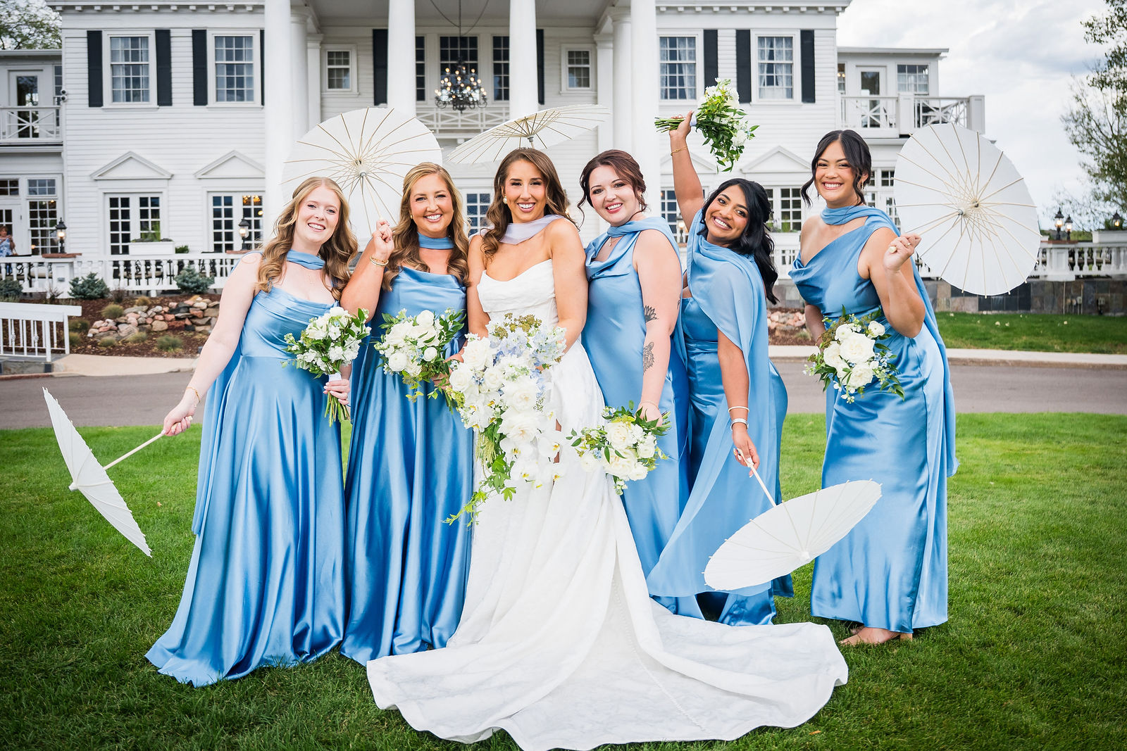 Bridesmaids in dusty blue dresses in front of the Manor House