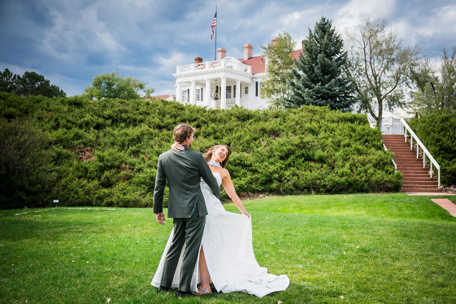 Groom dipping his bride on the lawn in front of the Manor House