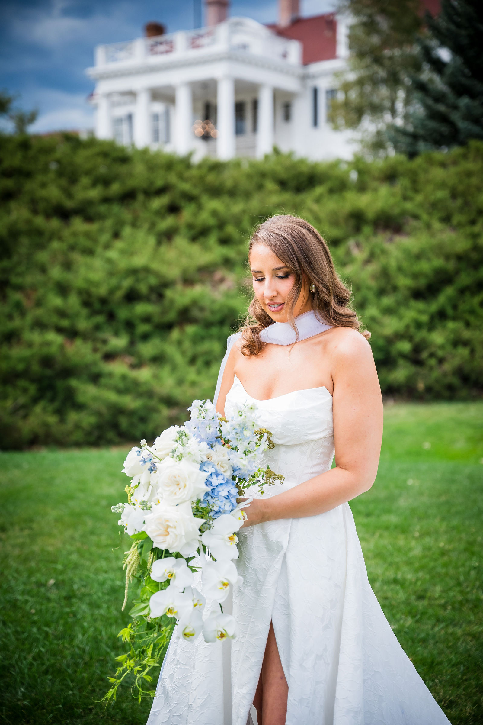Bride holding her white and blue bouquet outside the Manor House