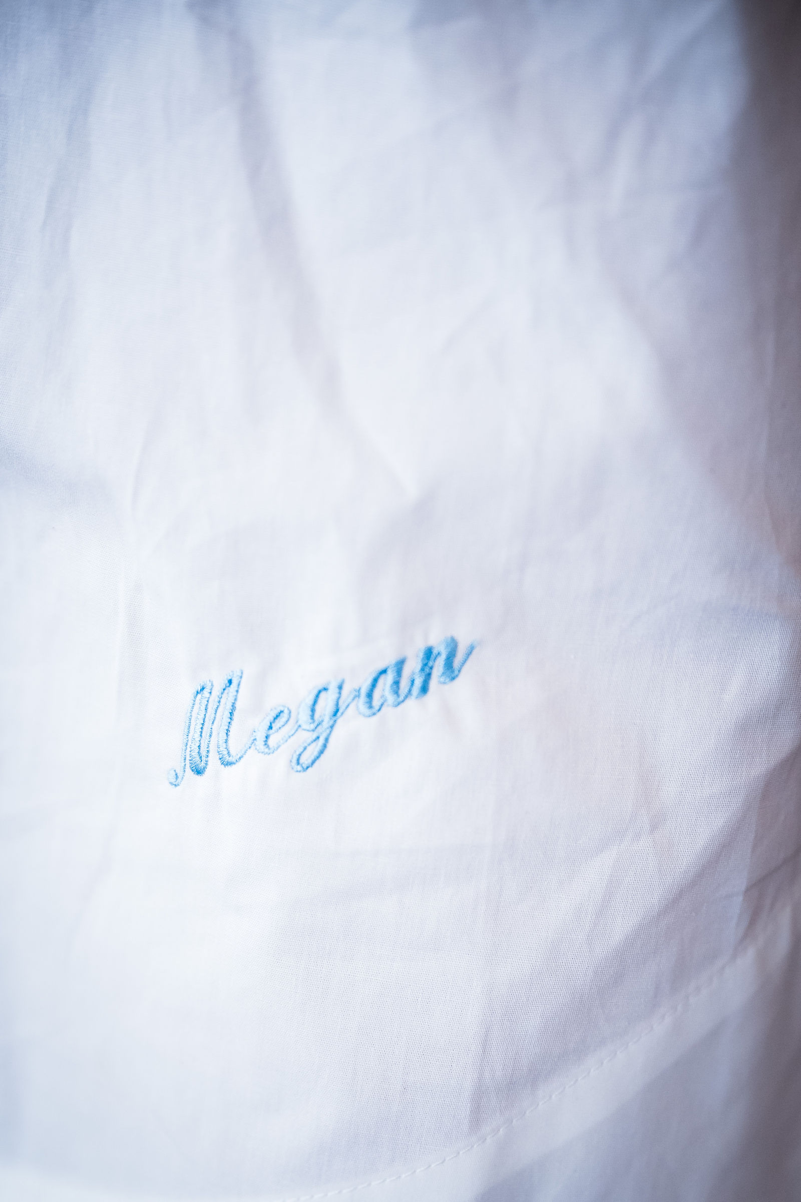 Bride’s white robe embroidered with her name in dusty blue