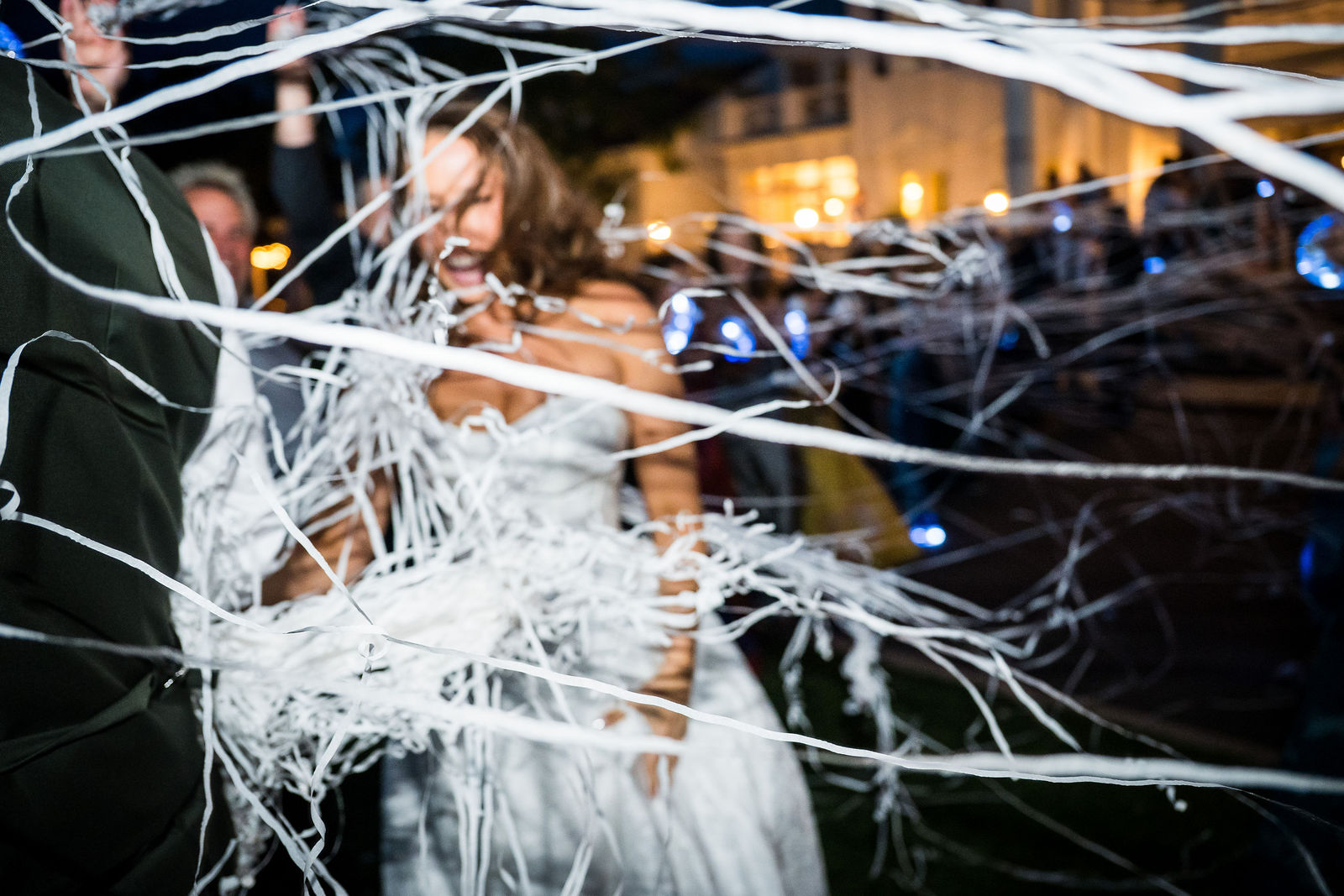 Newlyweds kissing in the streamers outside the Manor House