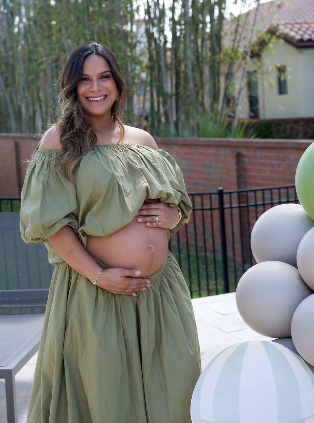 Mother-to-be in a sage dress at an elegant outdoor celebration