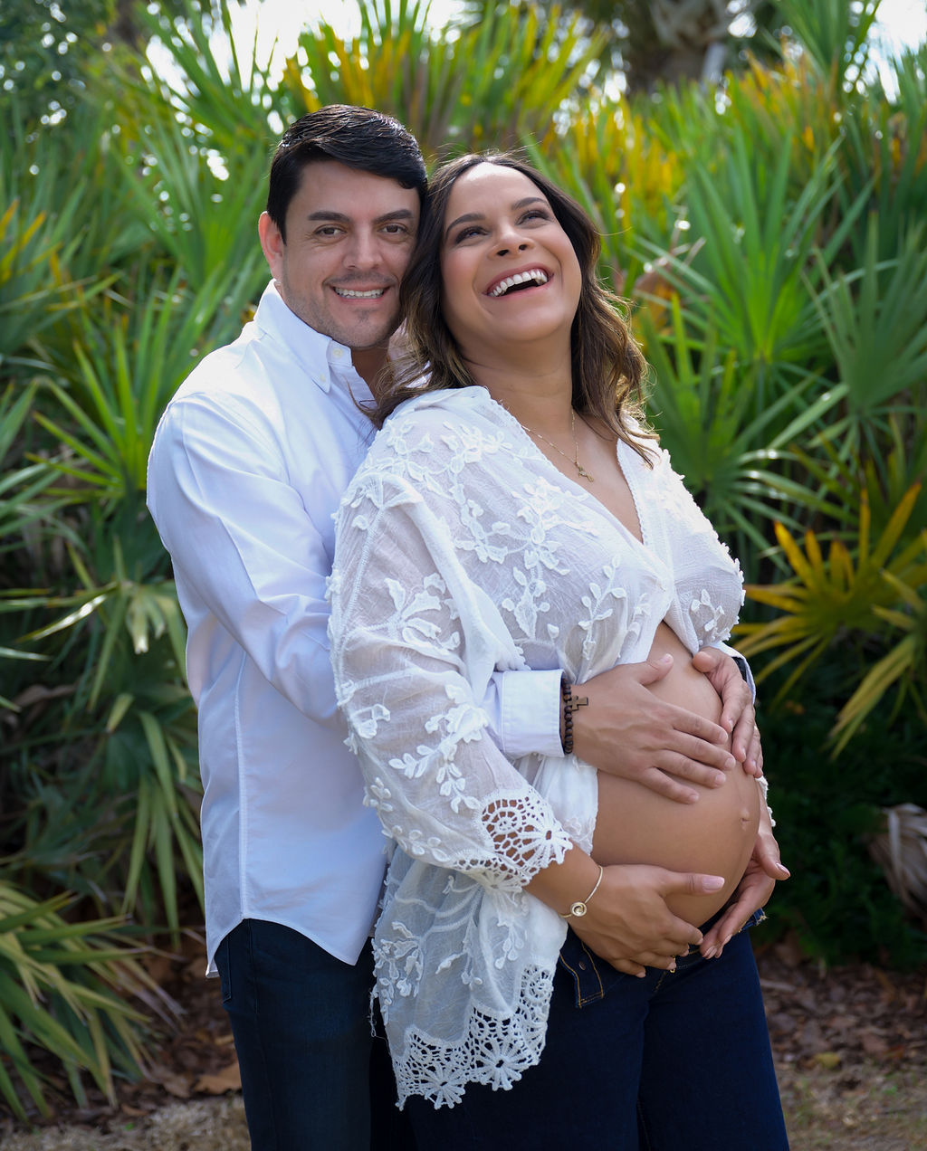 Expectant couple laughing together during a sunlit maternity portrait