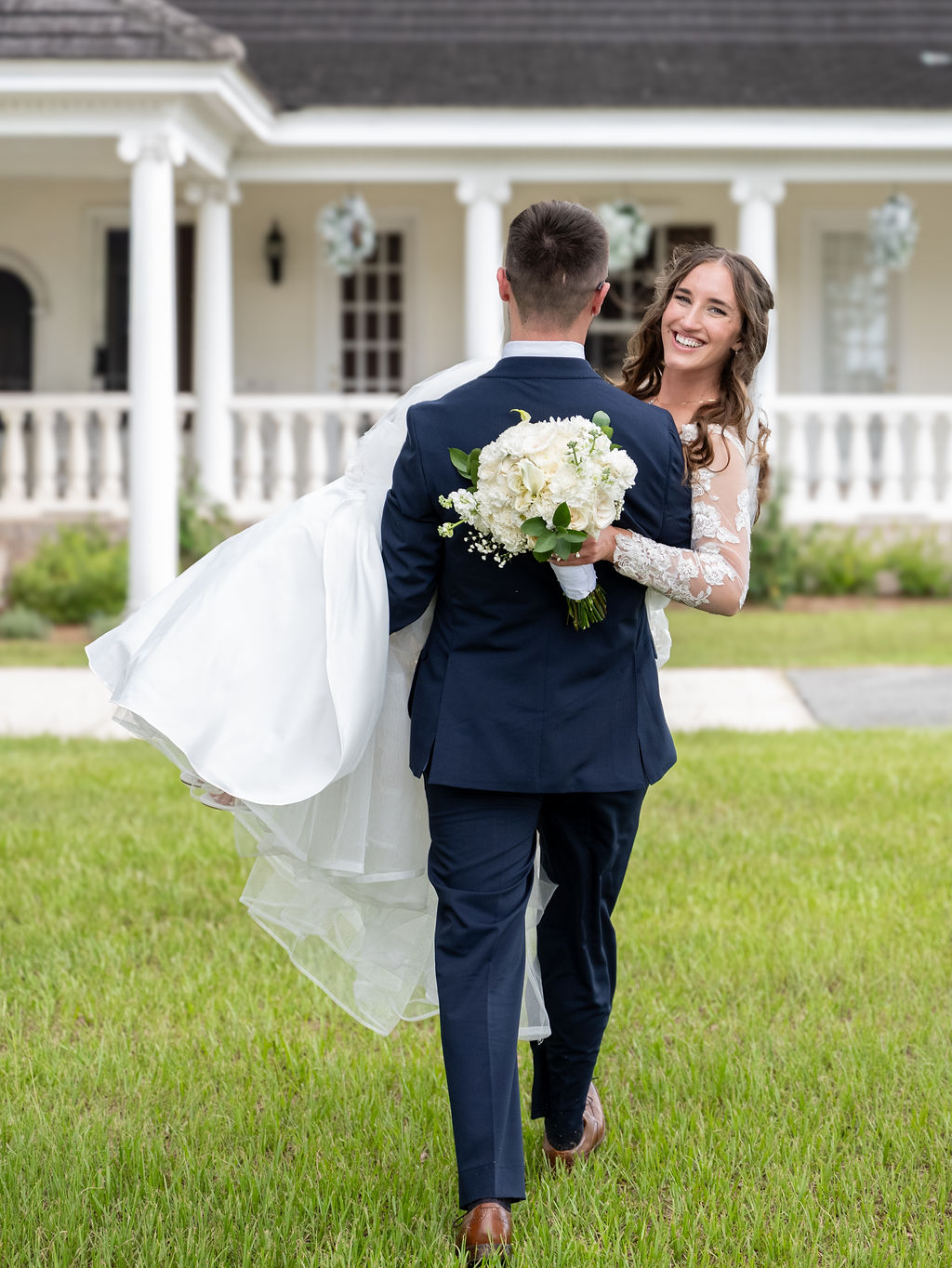 Newlyweds sharing a playful embrace on an estate lawn