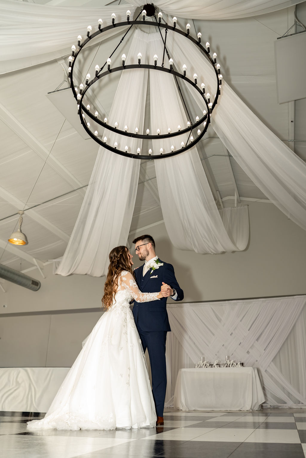 Wide view of a wedding dance beneath a sculptural chandelier