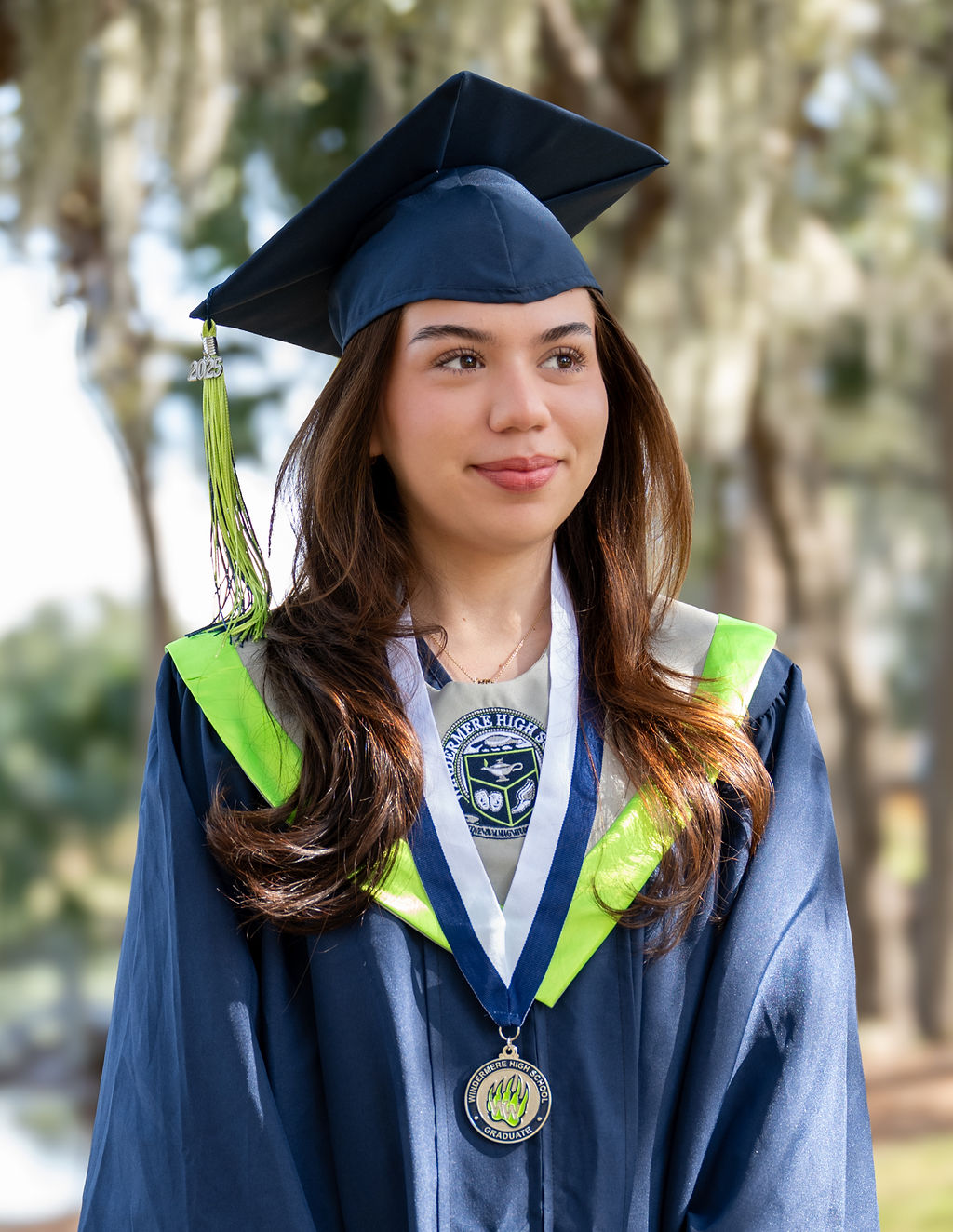 Graduate in a navy cap and gown wearing an academic medal