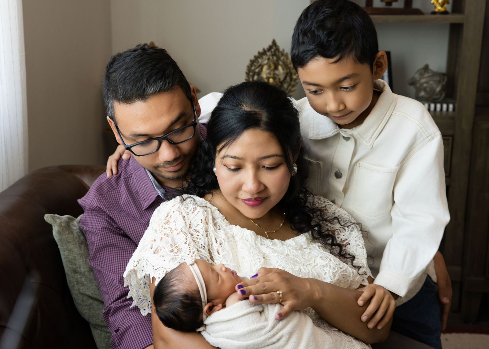 Lifestyle newborn photography in Utah County with parents holding baby near living room window