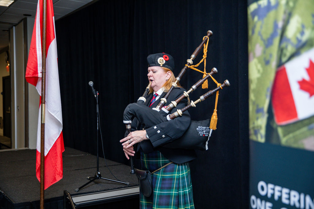 A piper playing beside the Canadian flag