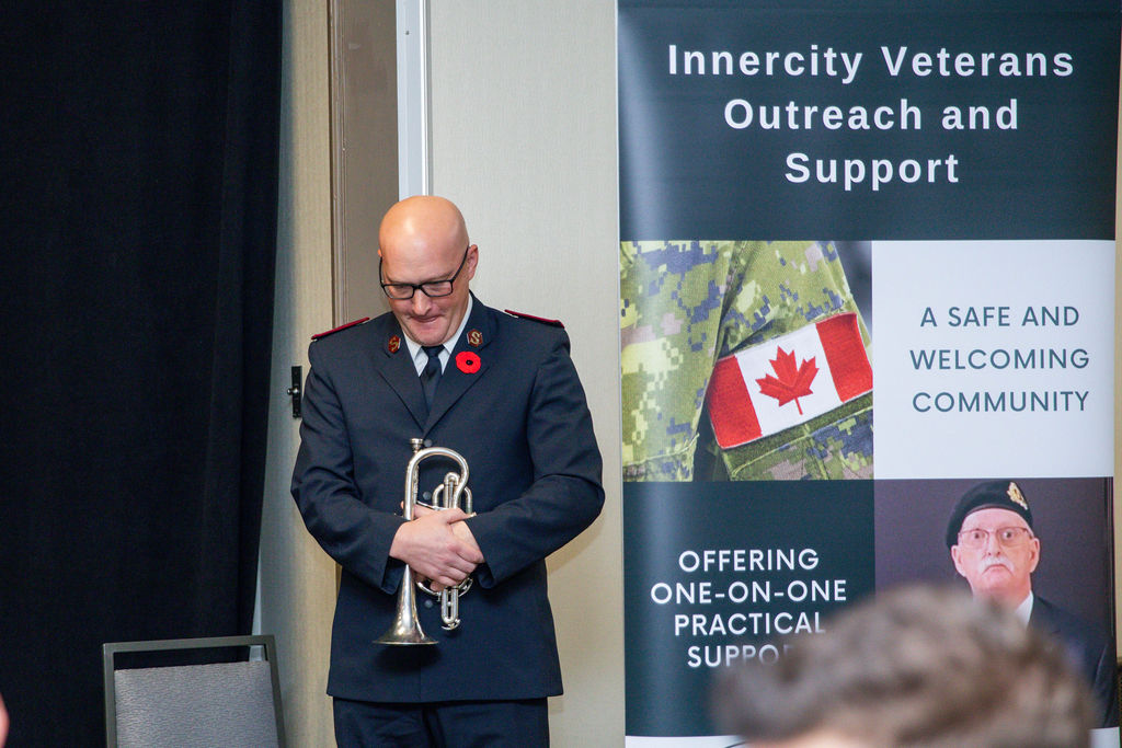 A bugler beside the Innercity Veterans Outreach and Support banner