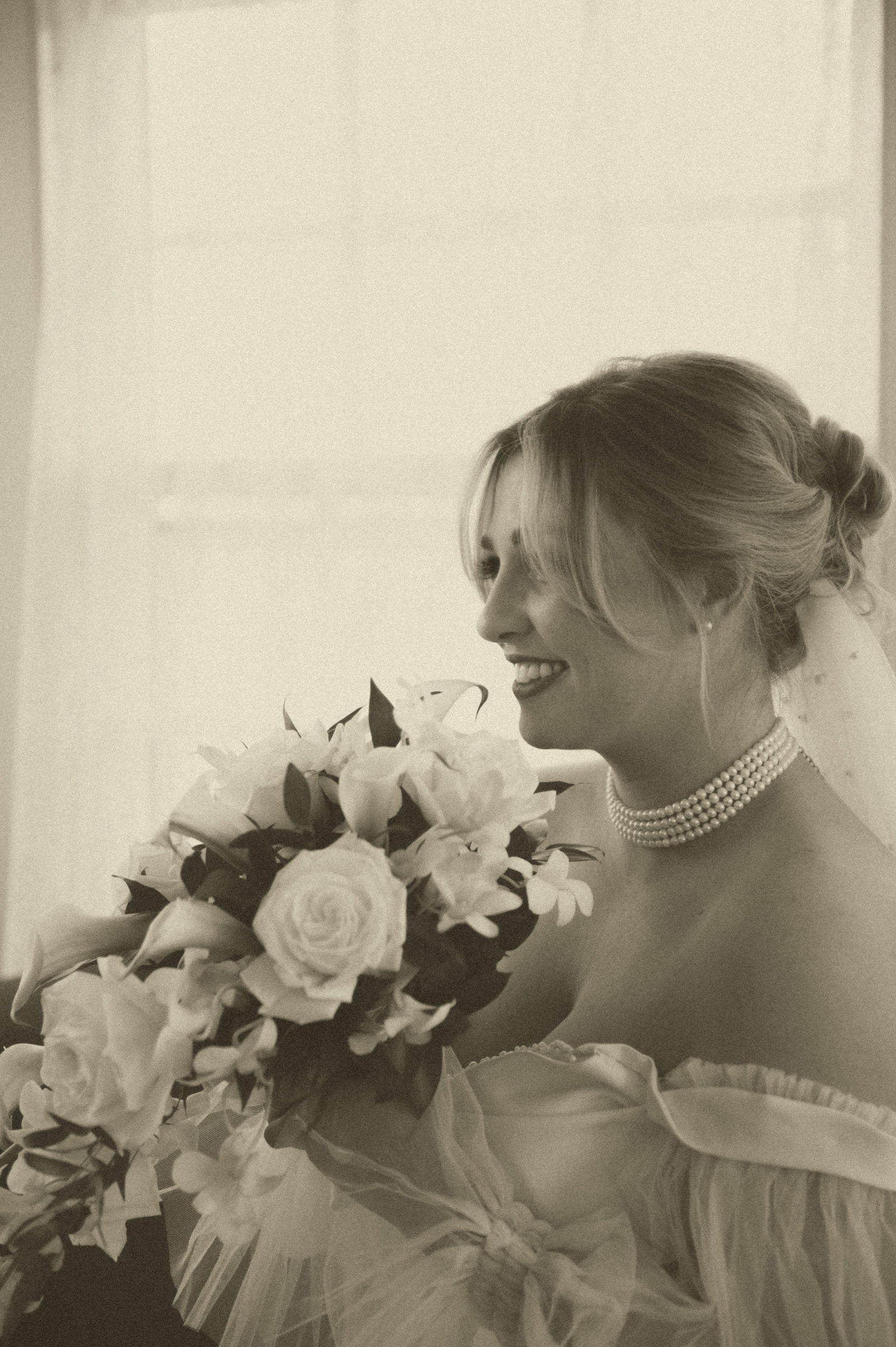 Bride holding her bouquet in soft window light with a vintage film tone