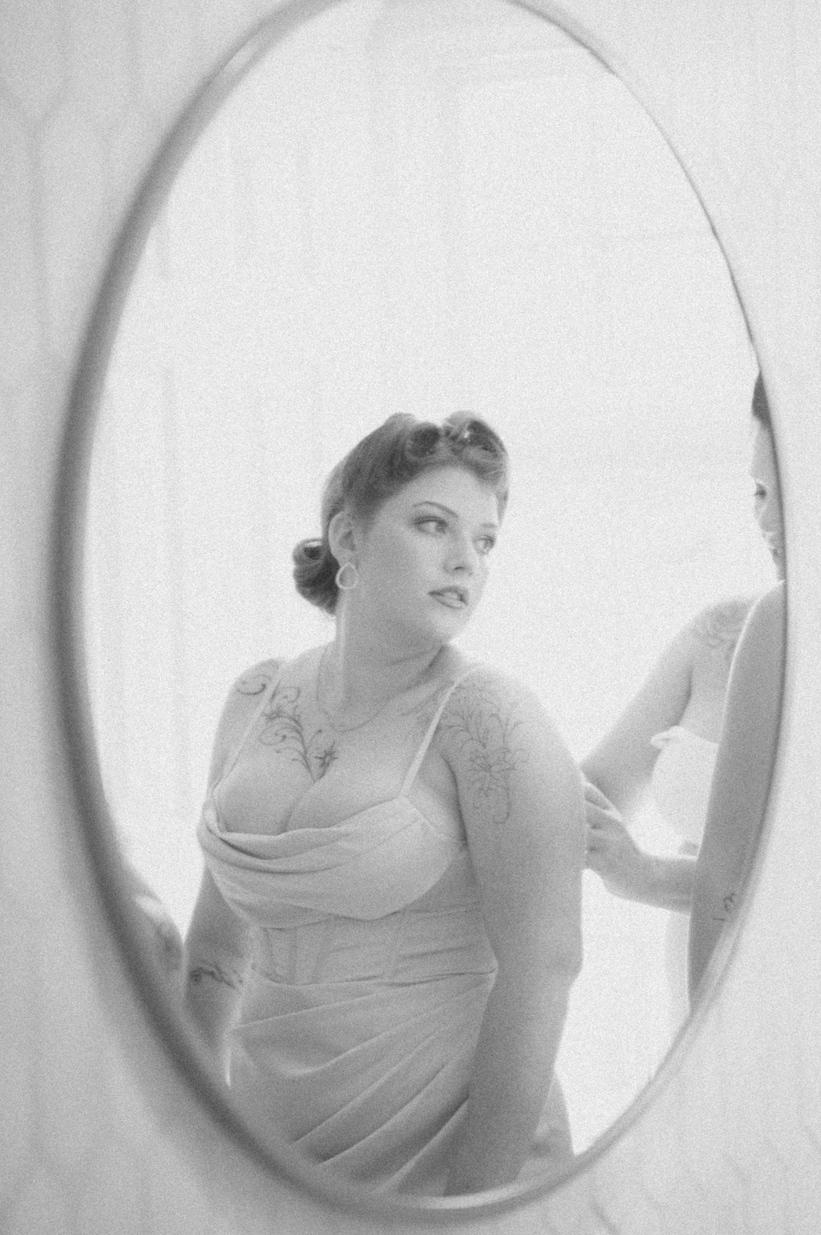 Bride looking into a mirror while getting ready for her old Hollywood wedding