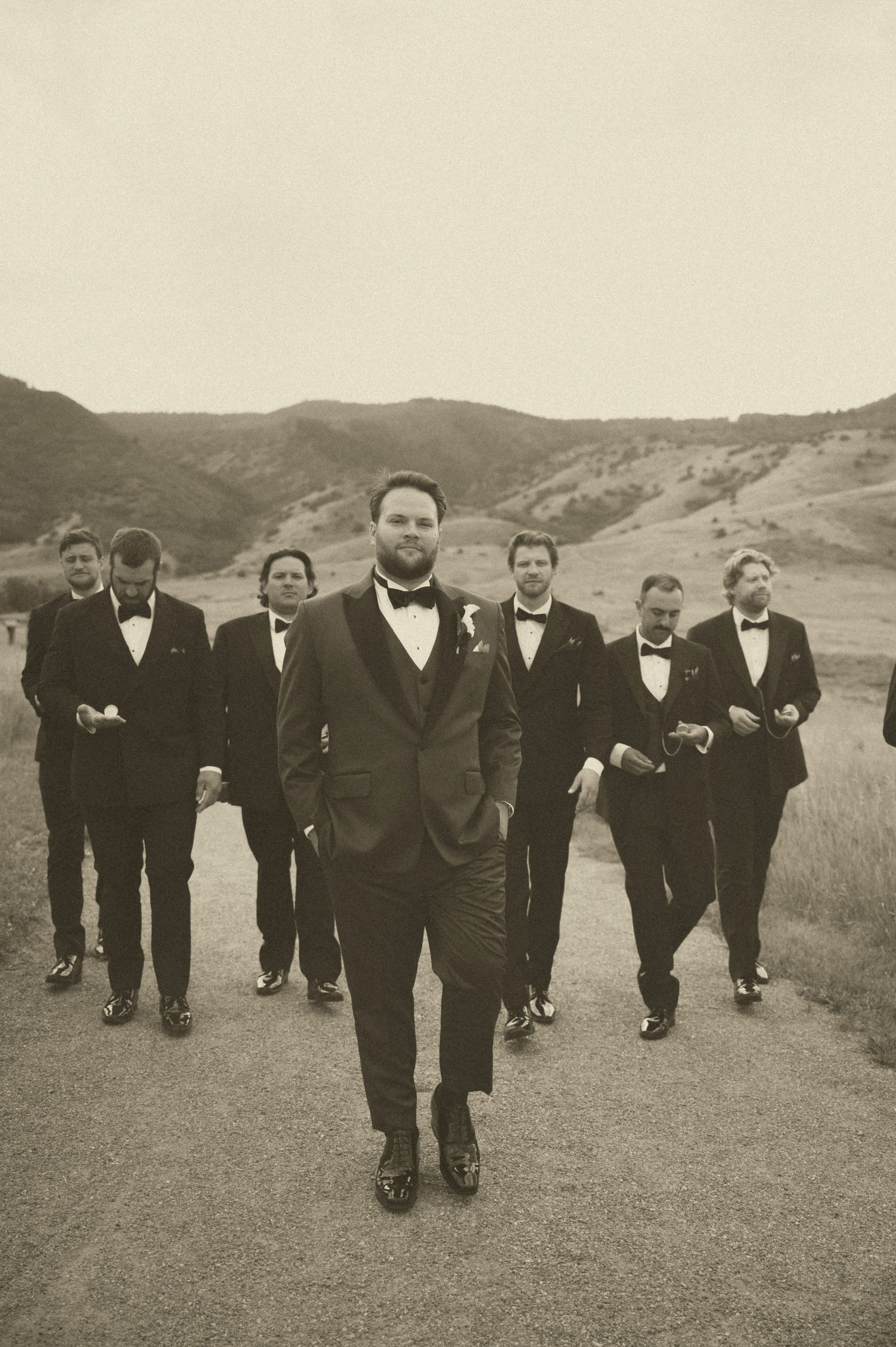 Groomsmen walking together toward the camera in black tuxedos