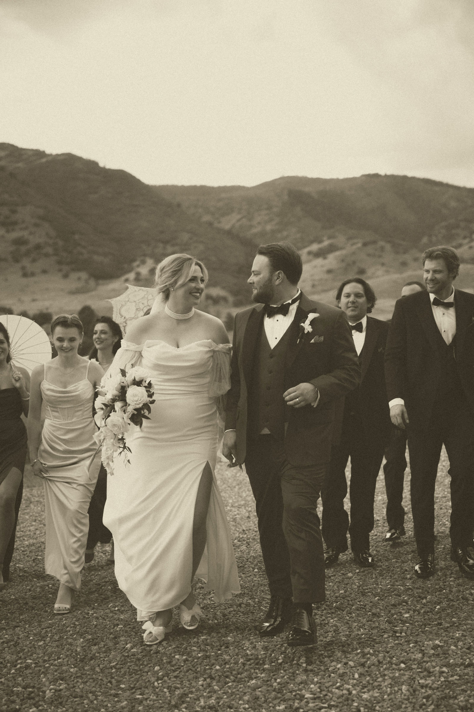 Groomsmen lined up in black tuxedos with the mountains behind them