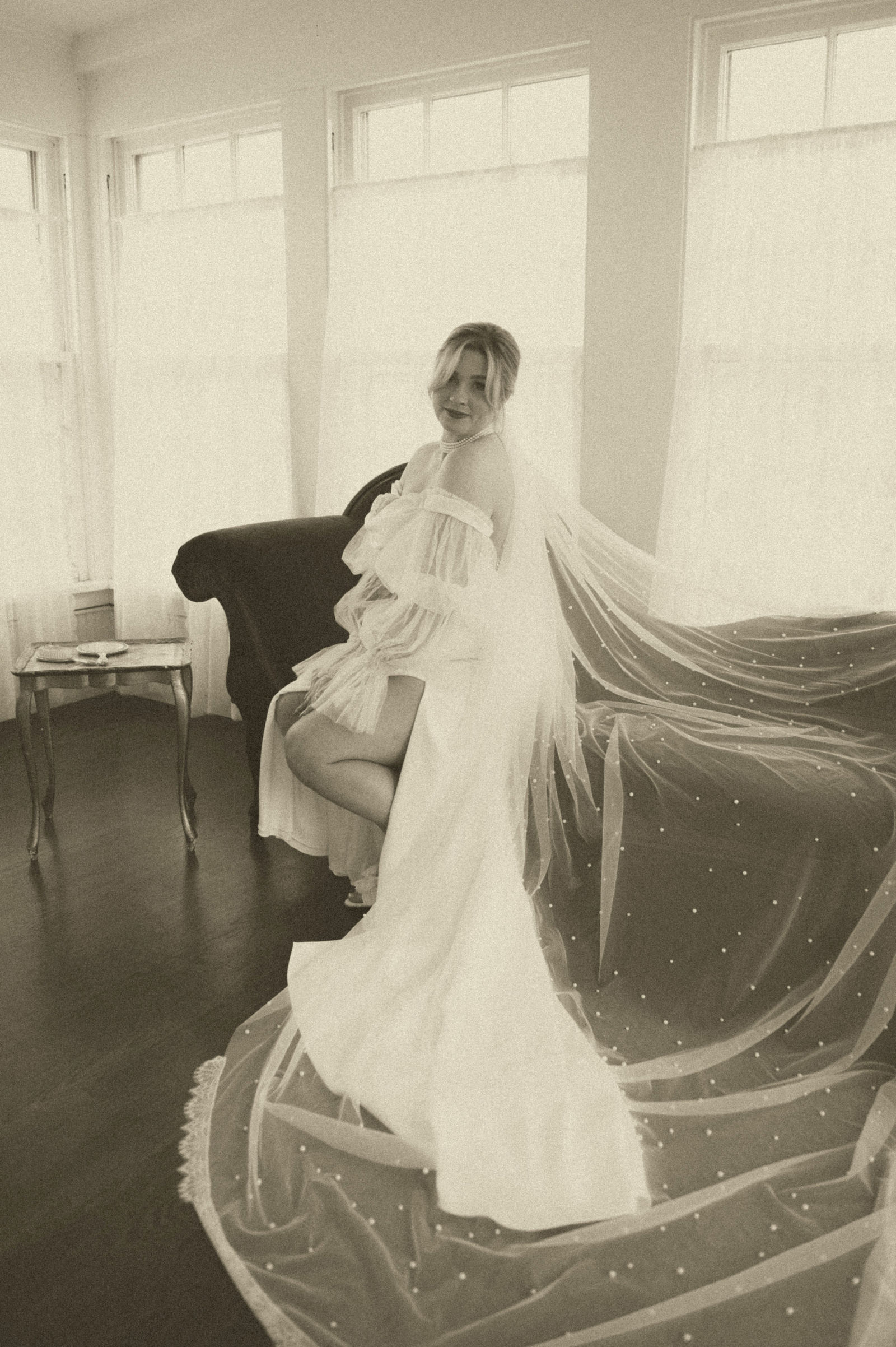 Long veil wrapping around the bride in soft window light