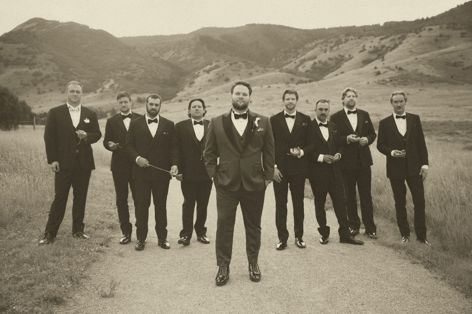 Groomsmen standing in a wide line for a 1920s styled group portrait