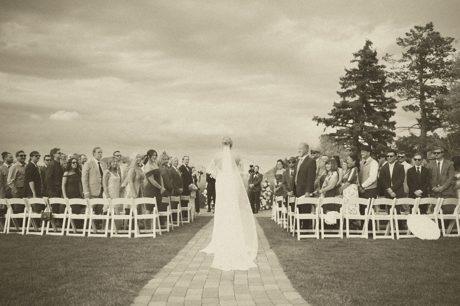 Wide view of the outdoor ceremony aisle lined with white chairs