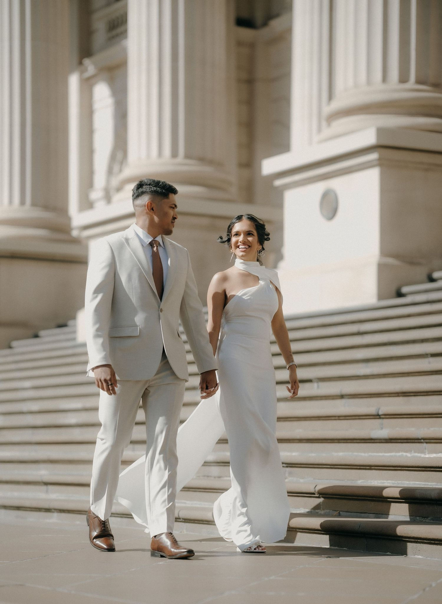 Bride and groom walking a coastal path at golden hour