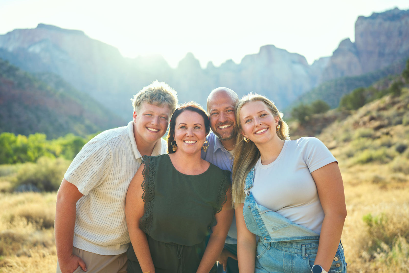 Close portrait of a family of four smiling together in warm sunlight