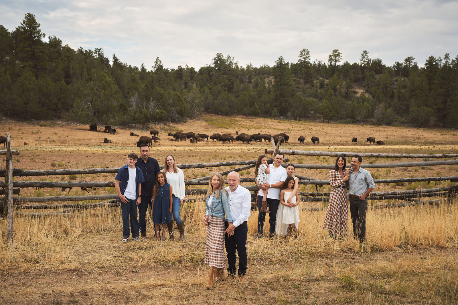 Large extended family portrait with bison behind them at Zion Mountain Ranch