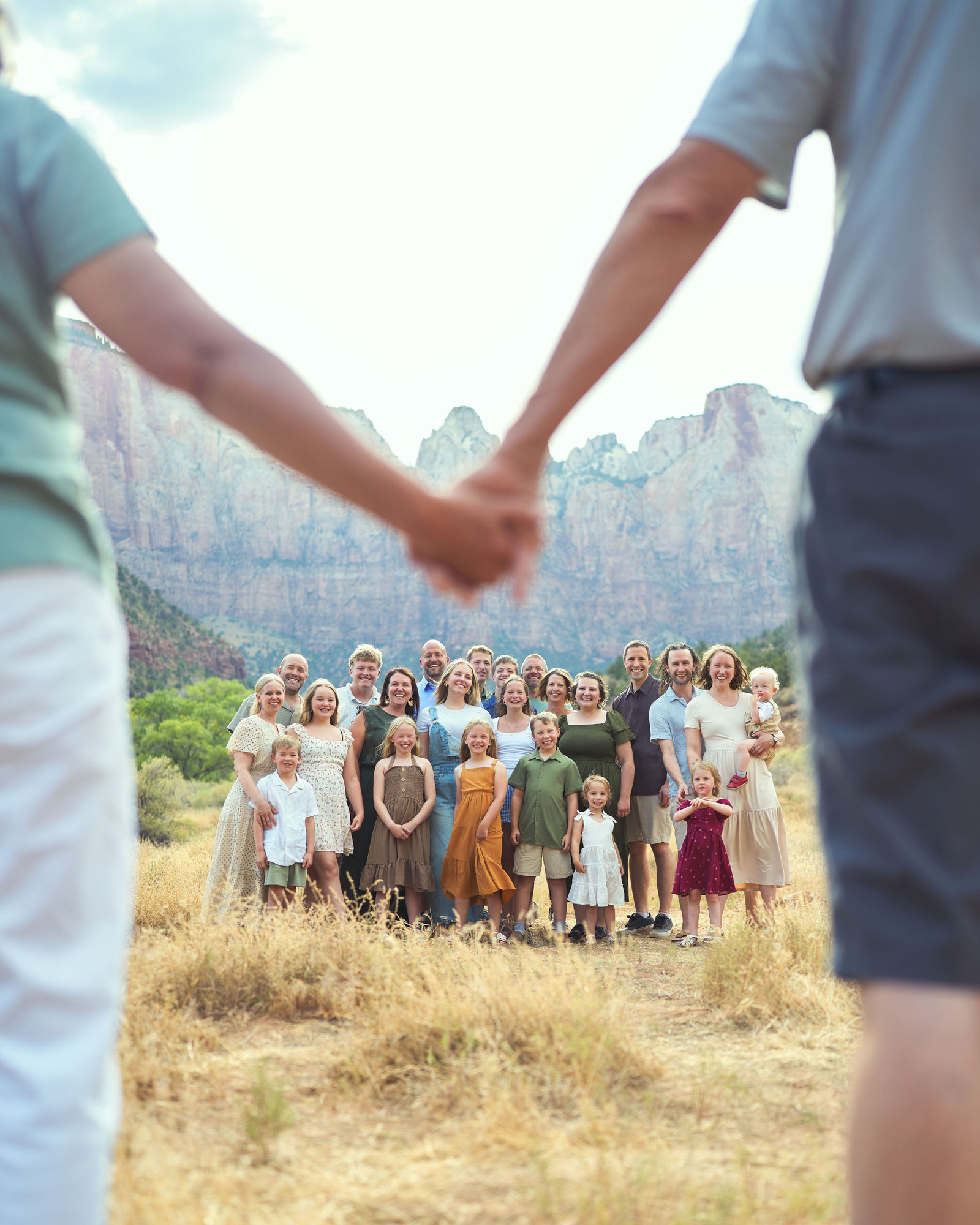 Grandparents holding hands in the foreground while looking toward their family