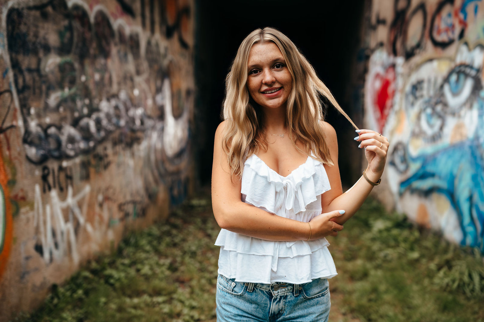 Syd in front of a graffiti-covered wall during her senior portrait session