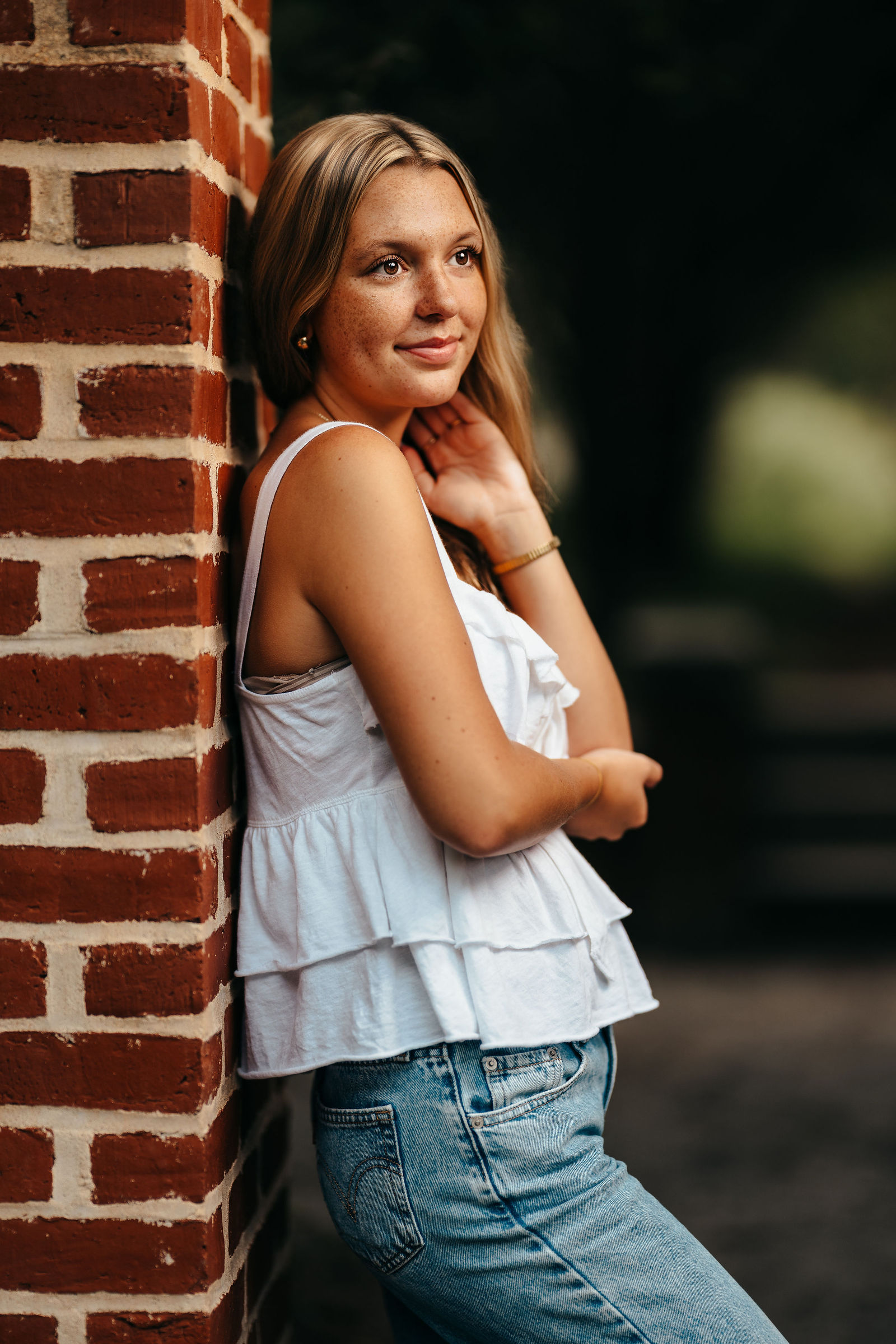 Syd leaning against a brick column during her senior portrait session in New Hampshire