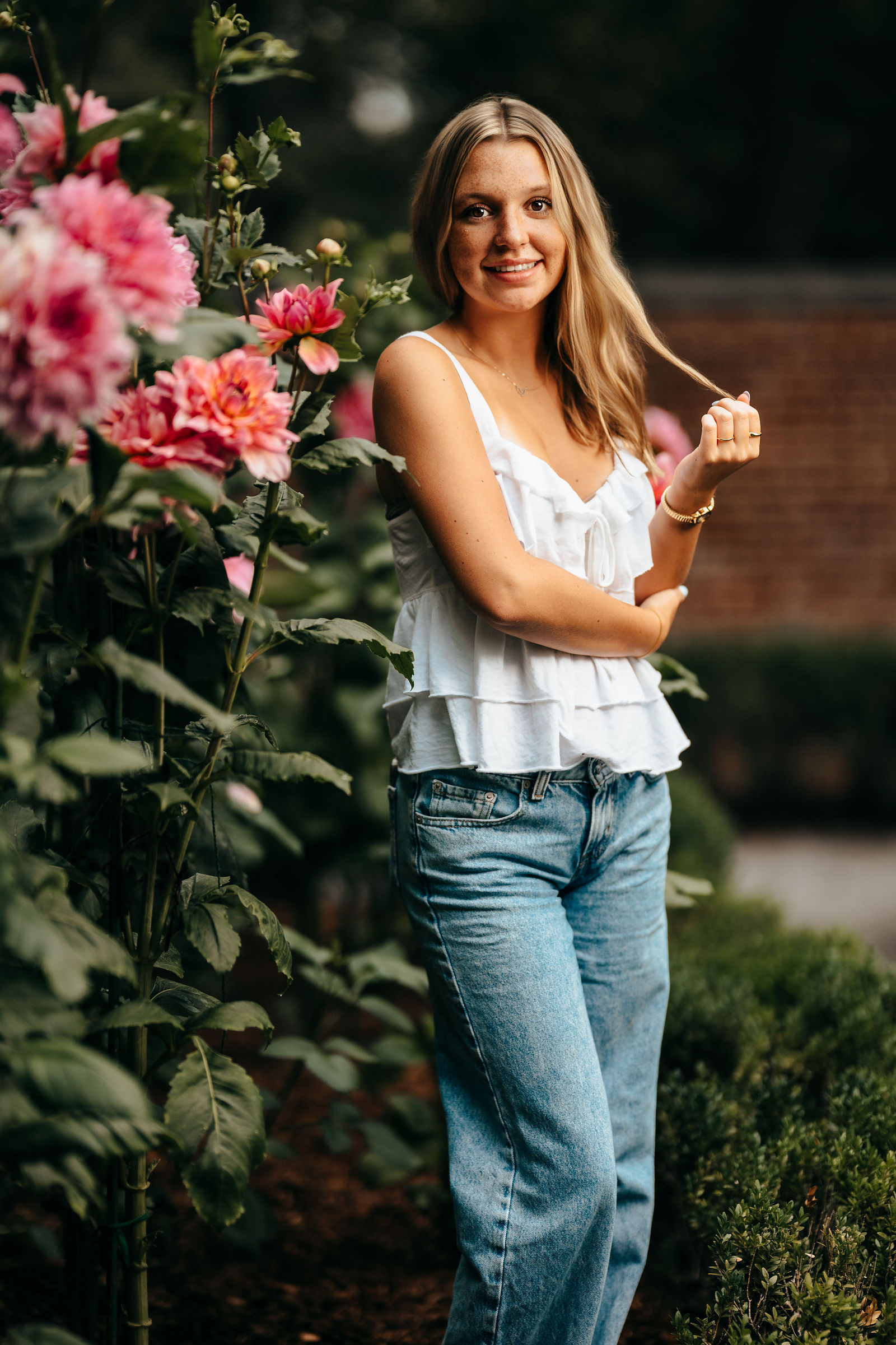 Syd in a garden of pink flowers during her senior portrait session