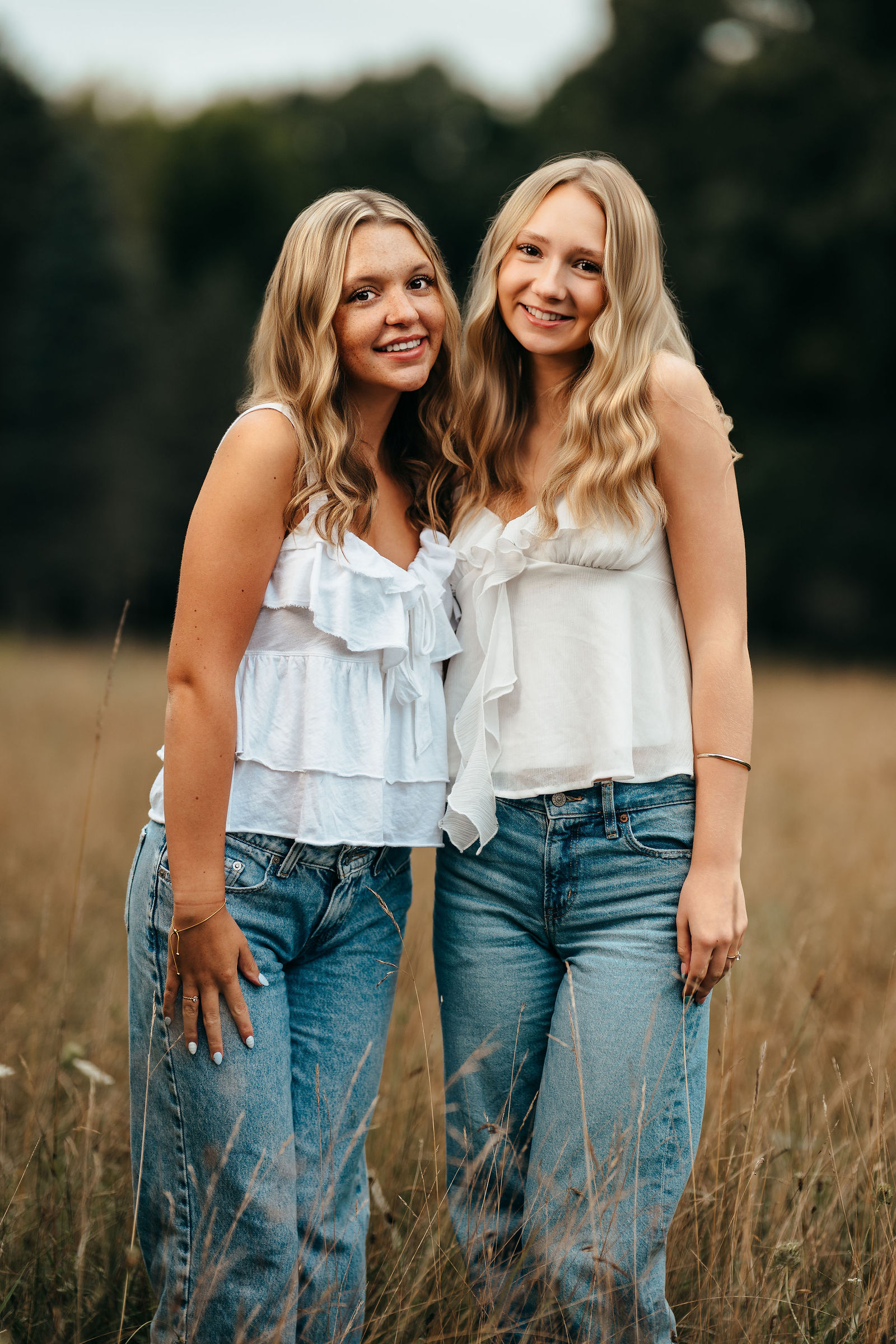 Syd and Aly standing together in a field of tall grass during their senior portrait sessions
