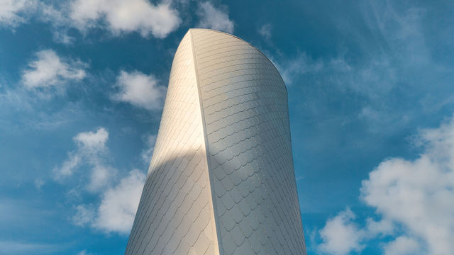 Arkitekturfoto av en modern byggnad med skifferliknande fasad mot blå himmel i Göteborg