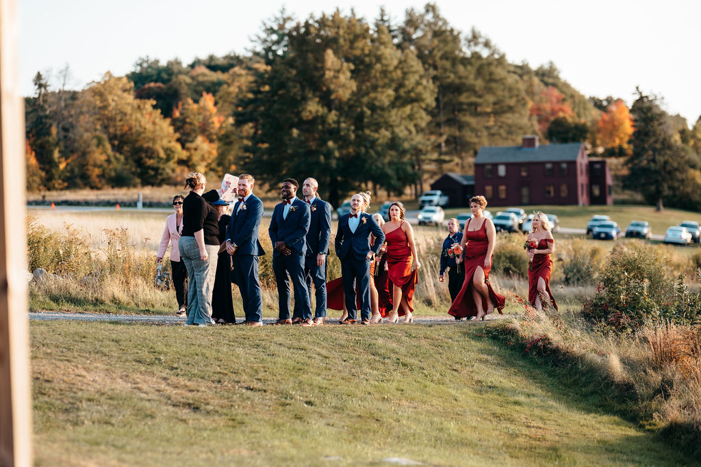 Wedding party walking with the red barn behind them