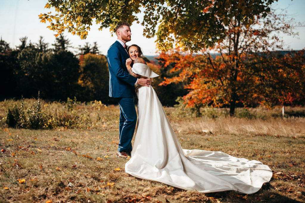 Samantha and McCallum kissing in a field of fall foliage