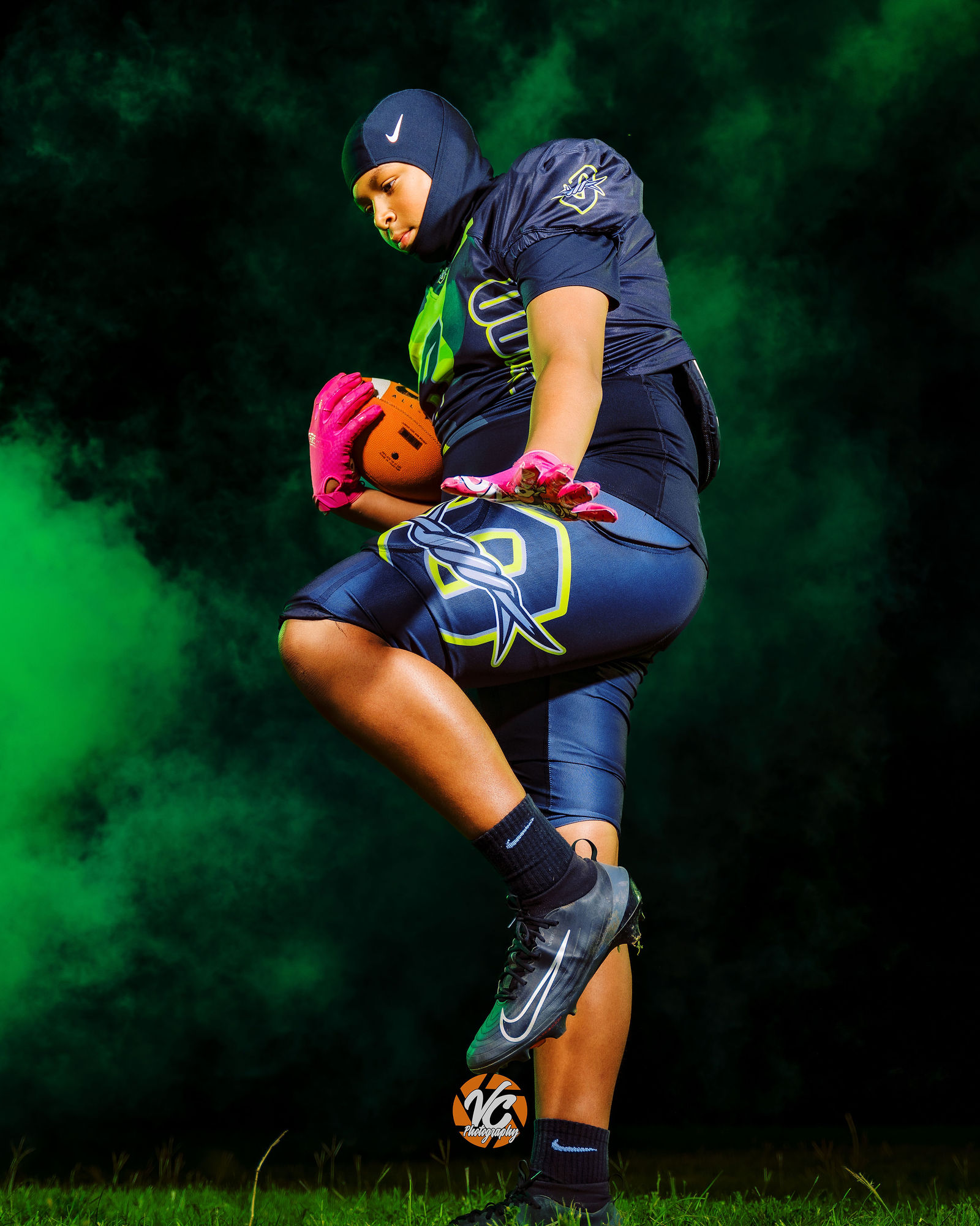Hays Outlaws football athlete kneeling in helmet and chains during a cinematic youth sports portrait session
