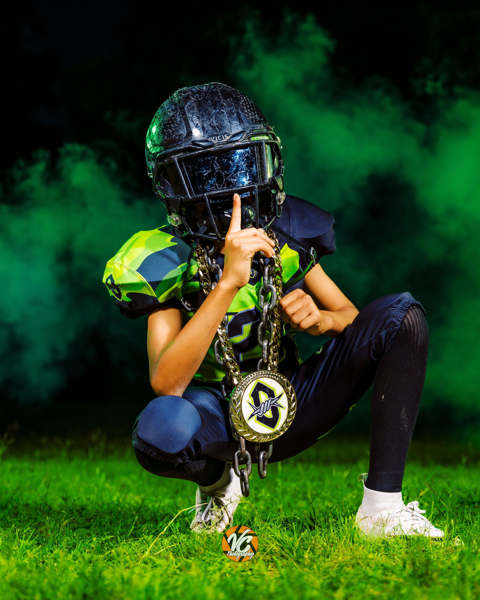 Hays Outlaws youth football player posing in helmet with green smoke during a professional media day in Buda Texas