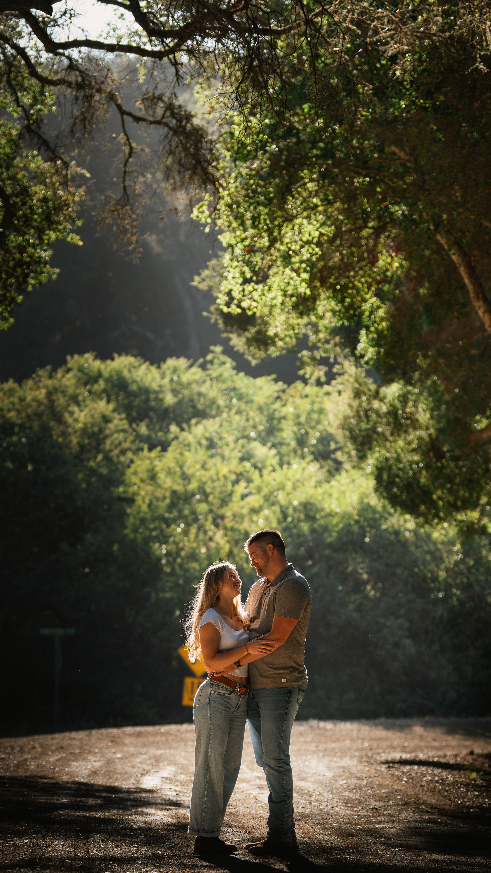 Engaged couple laughing together under oak trees at golden hour, Central Coast pre-wedding session