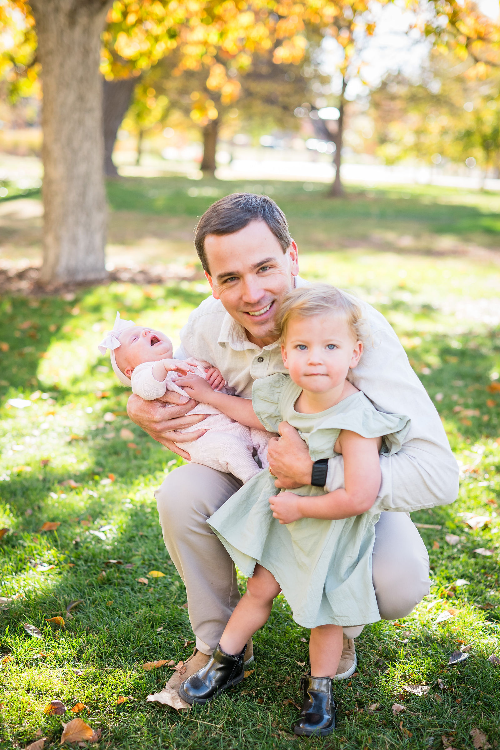 Dad in a cream shirt holding his two young children during a fall family session in Colorado