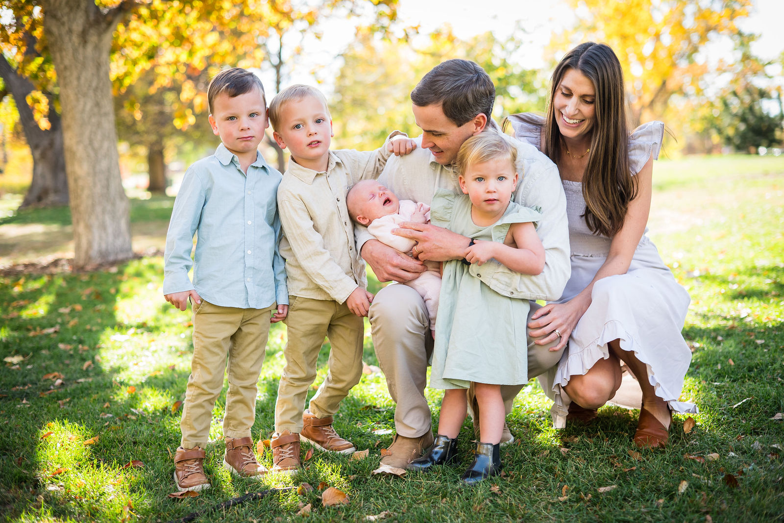 Parents and four young children in coordinated cream and khaki fall outfits in a Colorado park