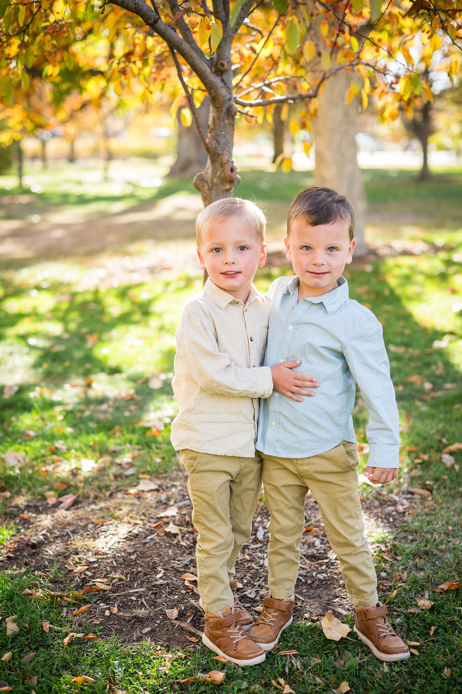 Two young brothers in coordinated cream and light blue fall outfits in a golden Colorado park