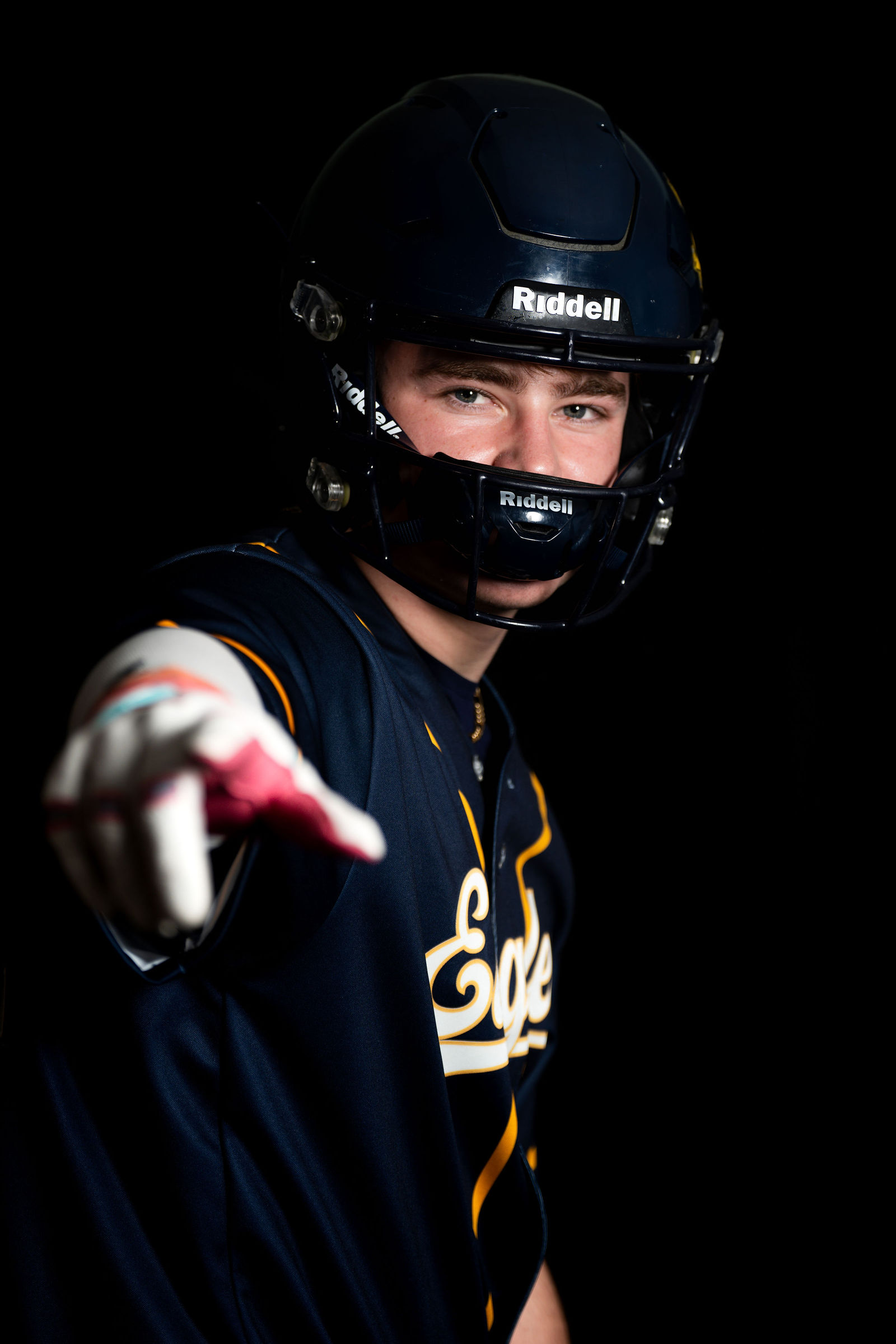 Football senior with Riddell helmet, pointing at camera, dramatic light