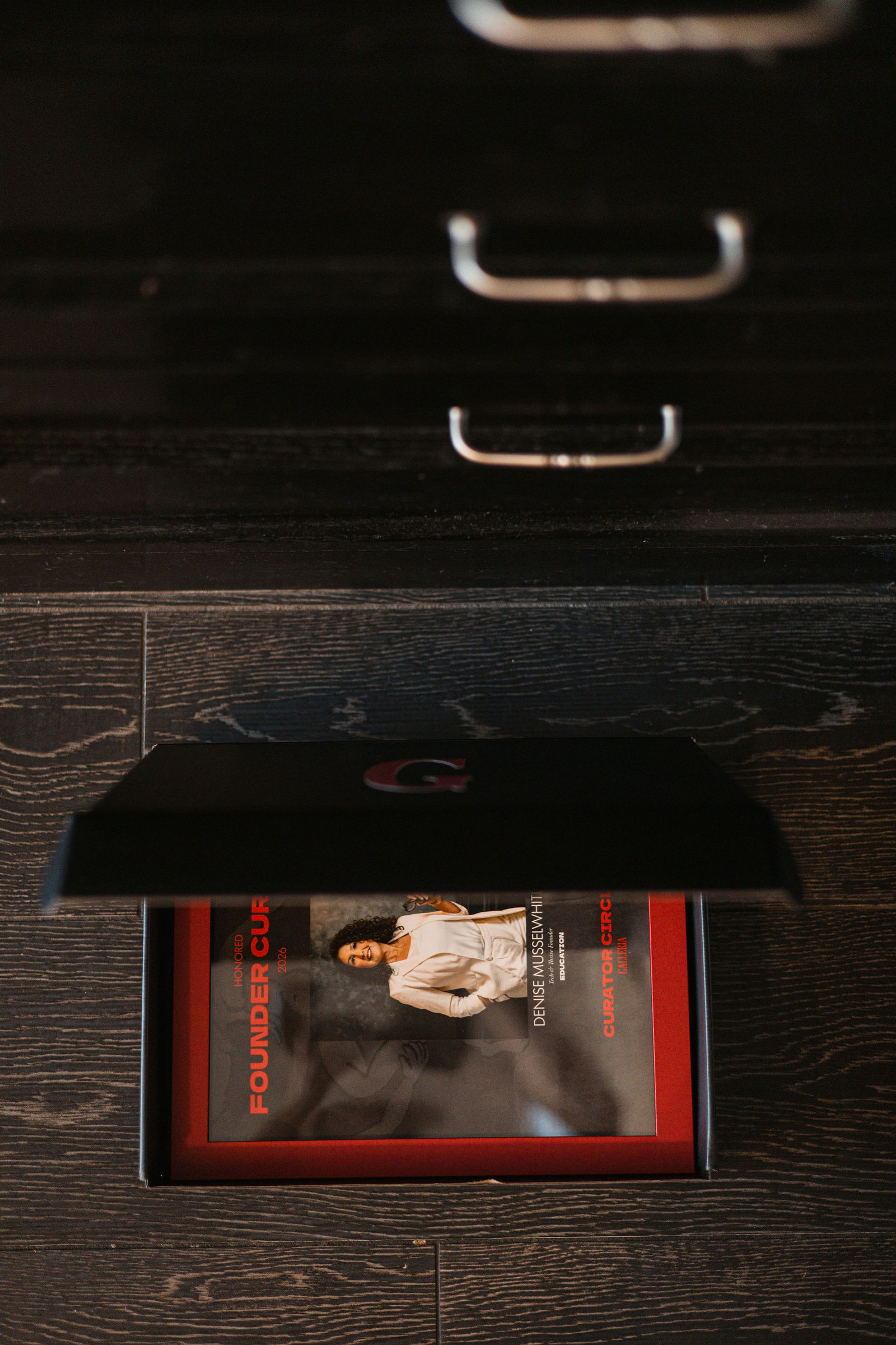 A plaque box with its lid lifted, on the dark wood table.