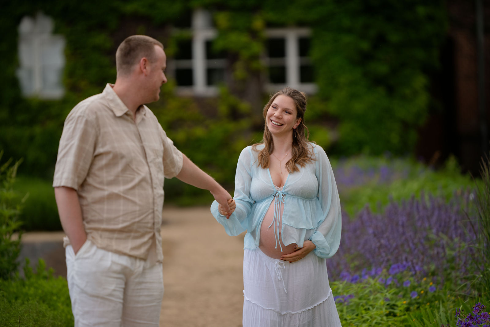 Werdende Eltern lächeln sich zärtlich an, sichtbarer Babybauch, natürliches Schwangerschaftsfoto in Berlin