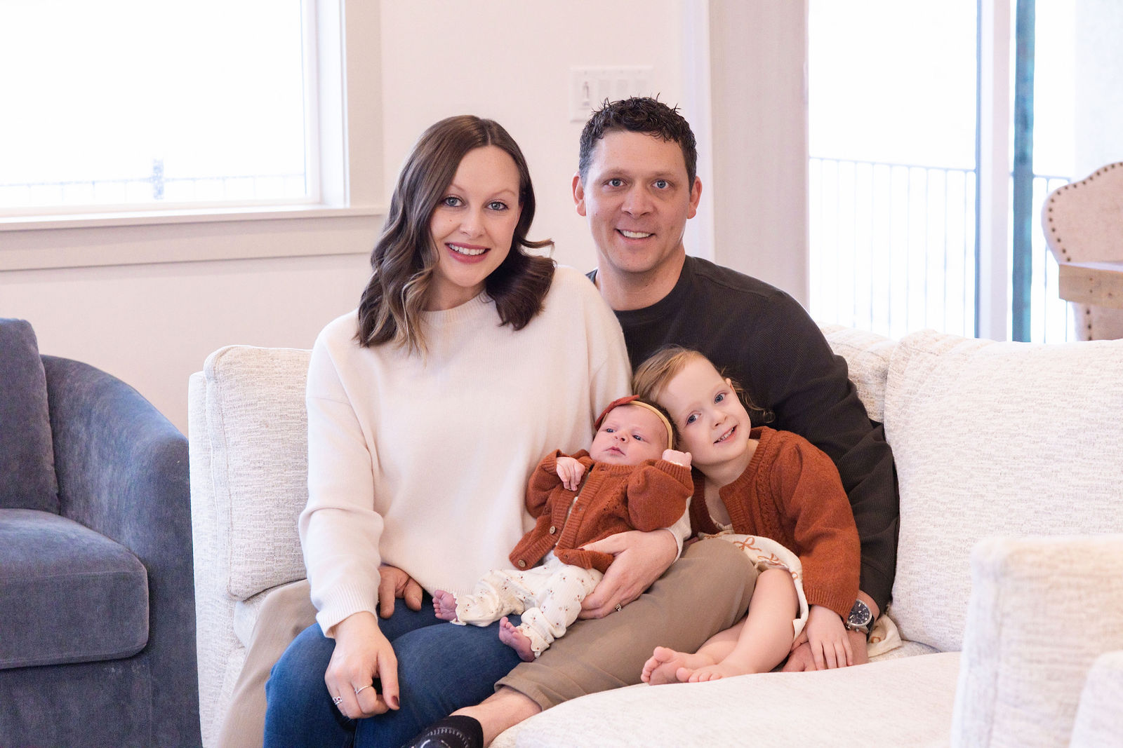 In-home newborn photography in Utah County showing relaxed family connection near natural window light