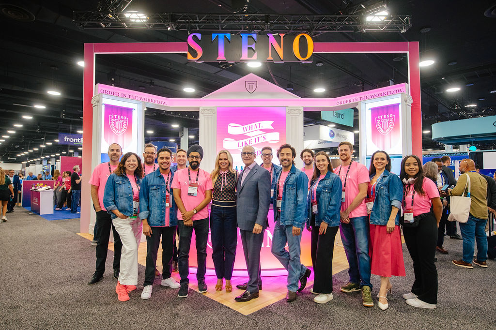 Full team photo in front of a branded trade show booth captured by an event photography company