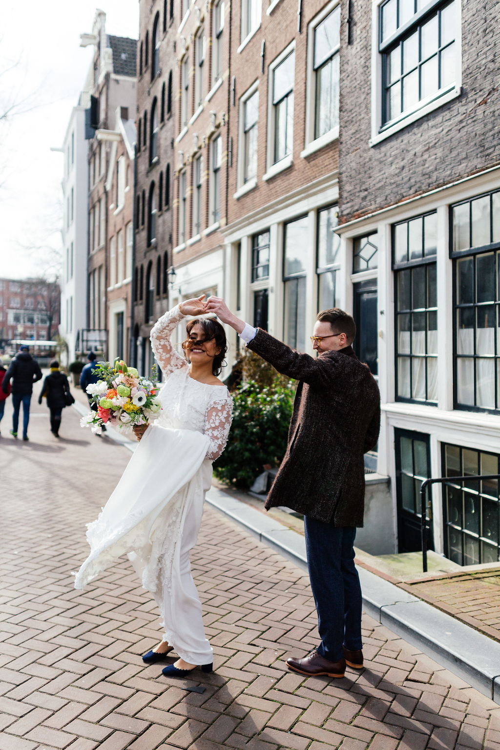 Le marié fait tourner la mariée dans une rue pavée