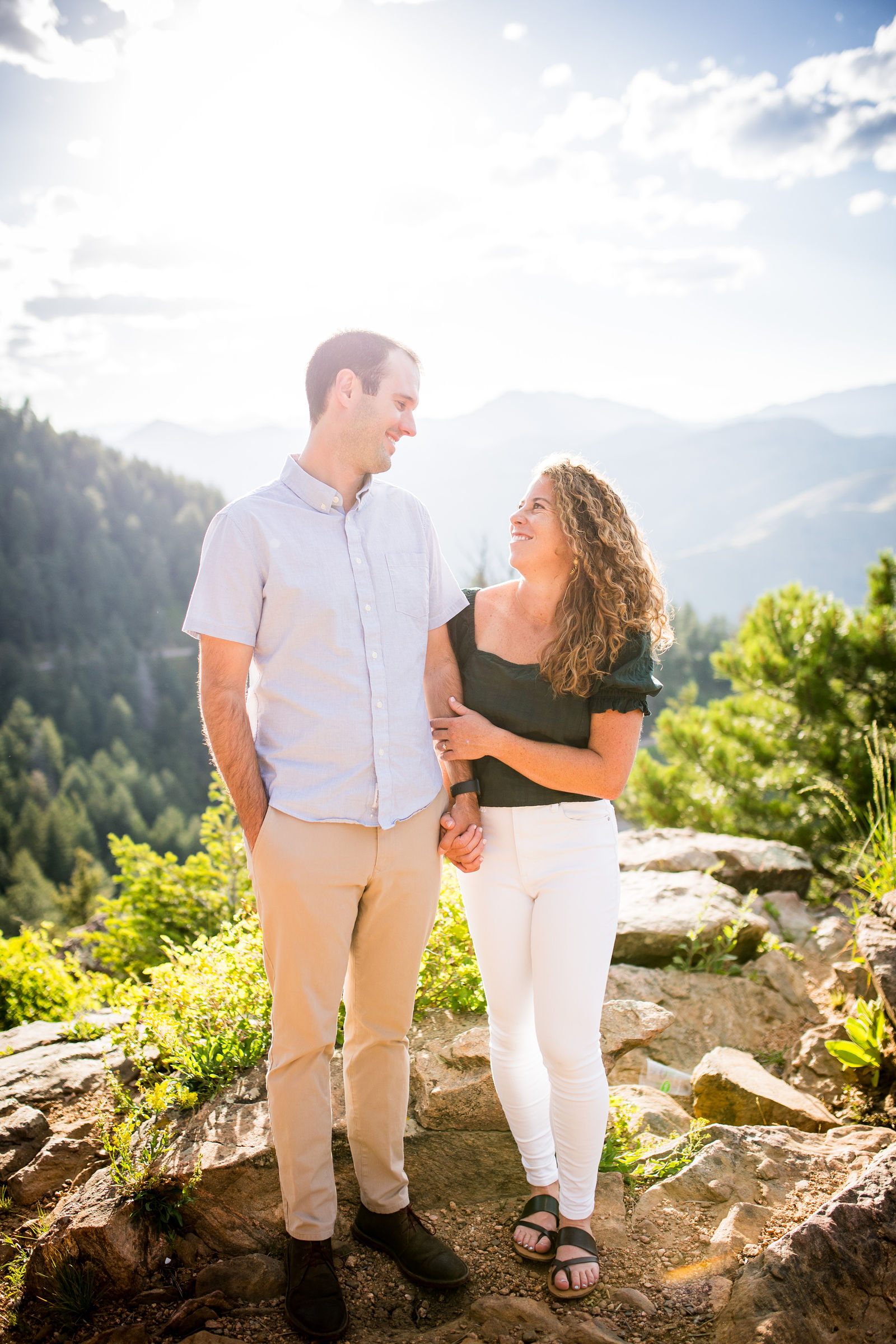 Engaged couple in a forest green top with cream wide leg pants and a pale blue shirt with khakis in Colorado