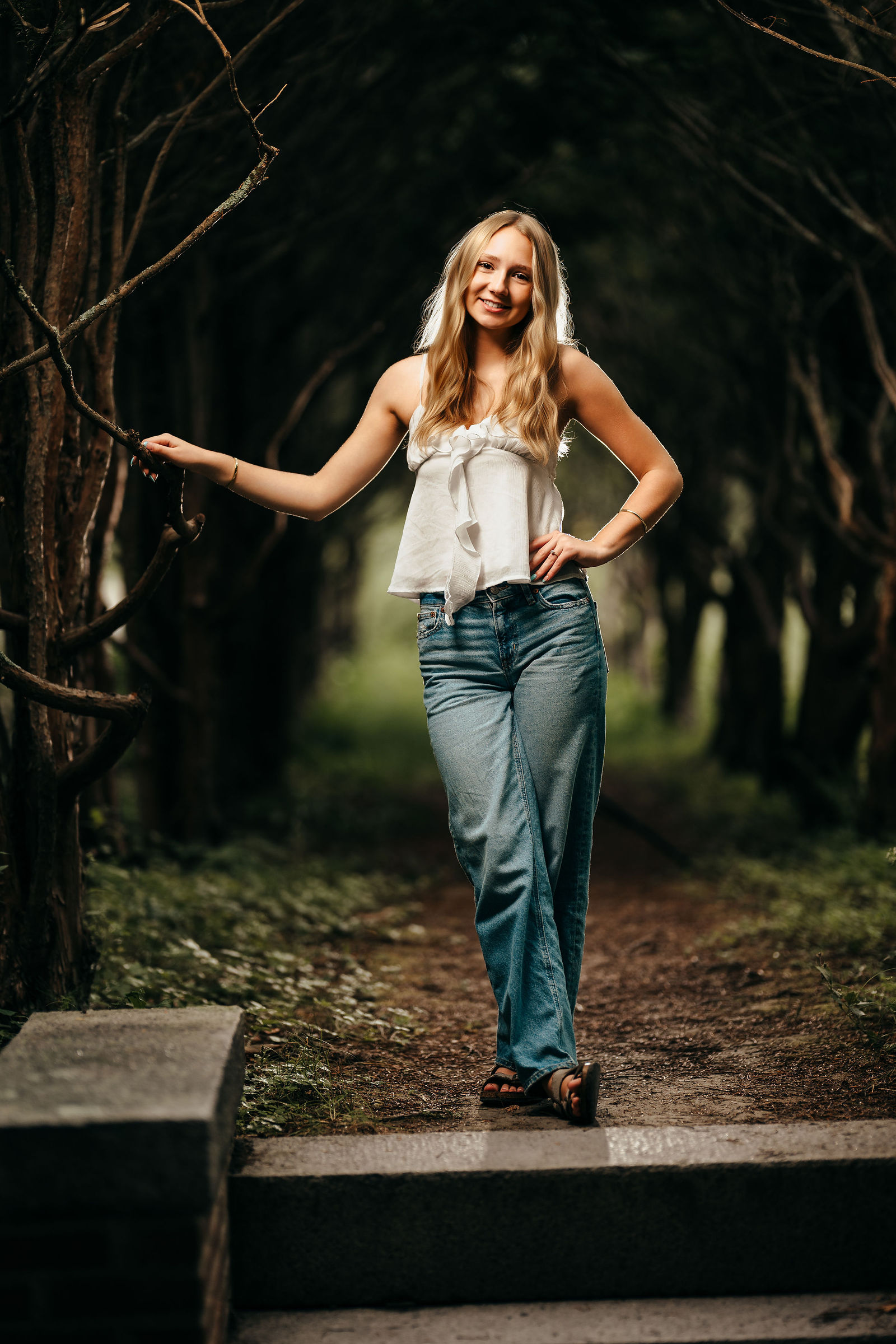 Aly walking under a dark archway, backlit, during her senior portrait session