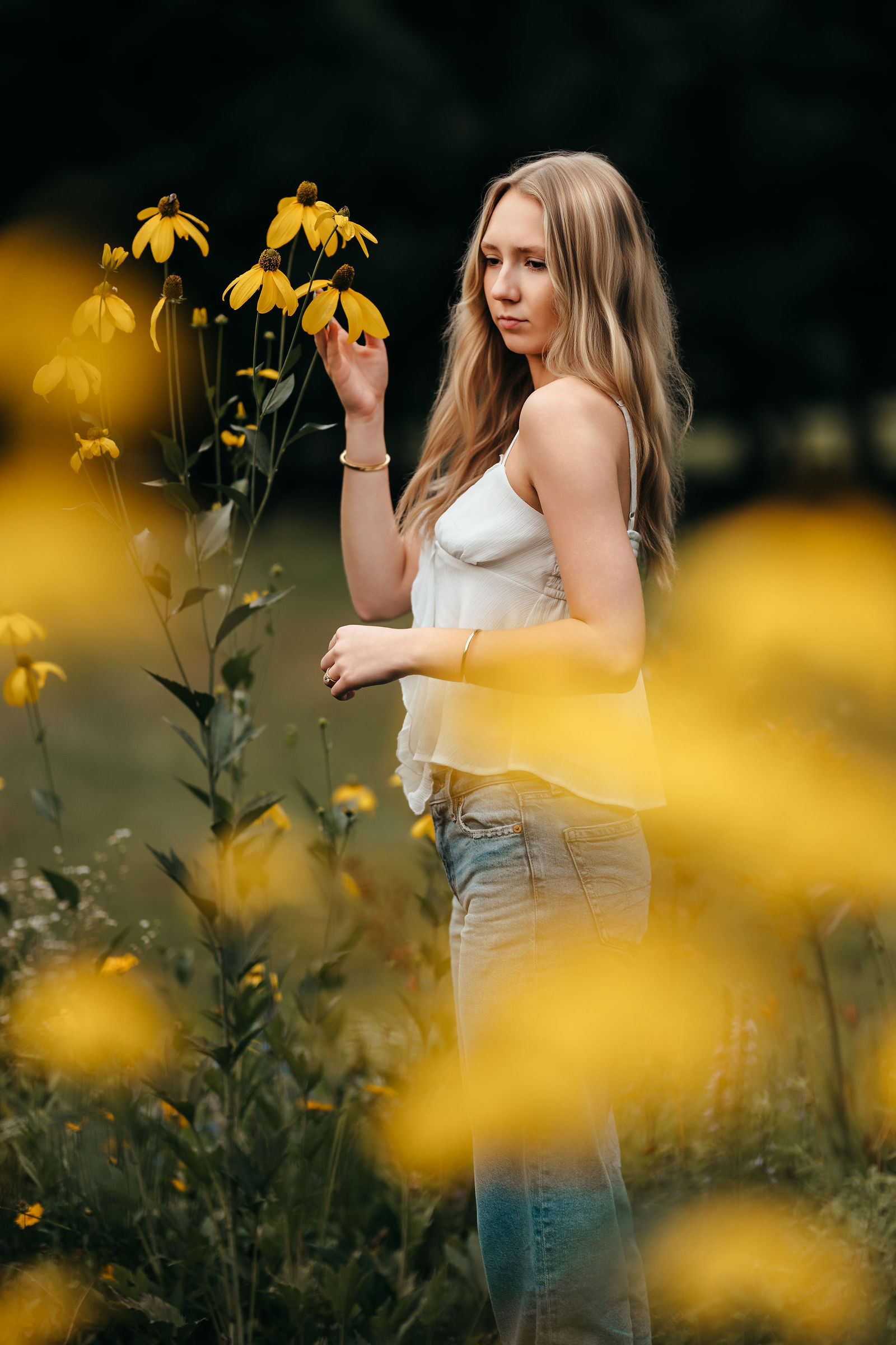 Aly standing in a field of yellow wildflowers during her senior portrait session in New Hampshire